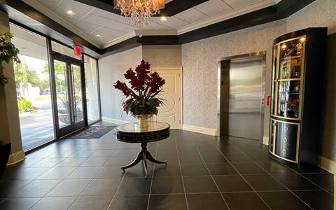 Ground-floor lobby with tiled floor, chandelier, a round table and the elevator