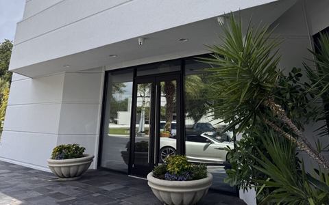 Main entrance with glass doors and planters under the building sign