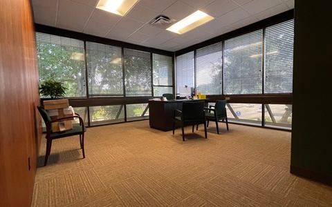 Corner office with wood panelling, carpet and windows on two sides