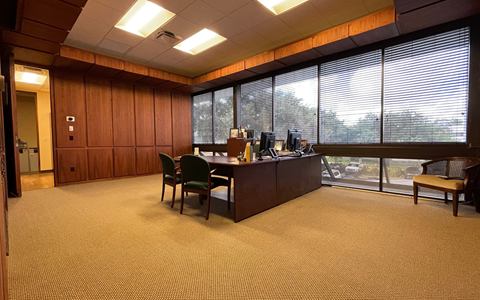Private office with a desk, wood-panelled wall and a bank of windows