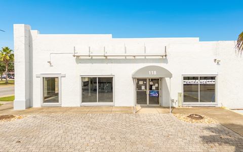 Main entrance under the 118 awning, with showroom windows and a paver forecourt
