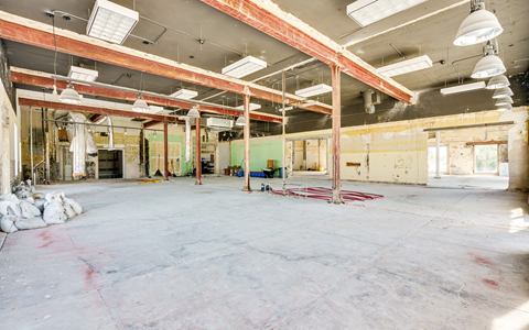 Open showroom interior with exposed steel beams, high ceiling and bare concrete floor